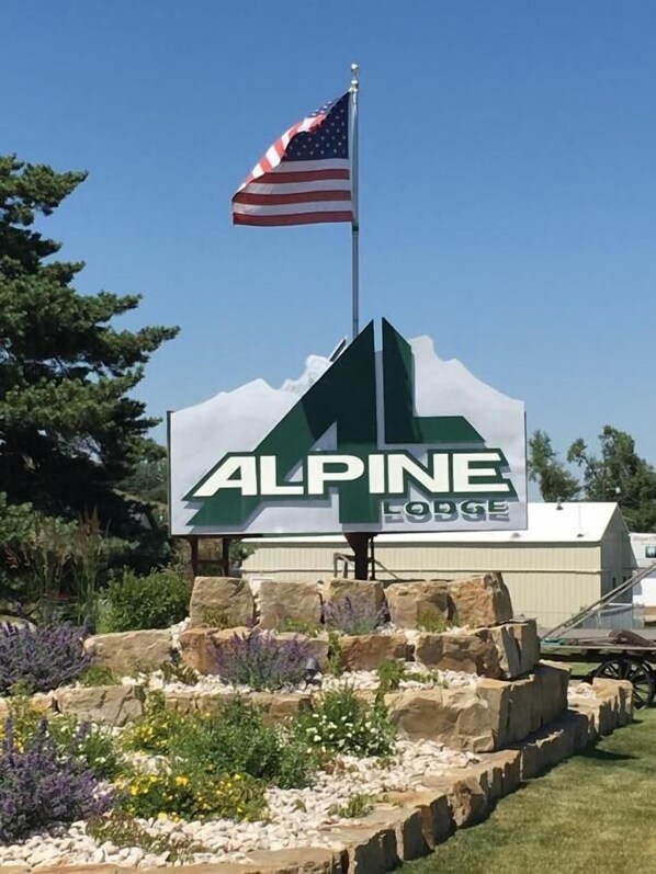 A sign for 'Alpine Lodge' with a flagpole and a mountain-like design.