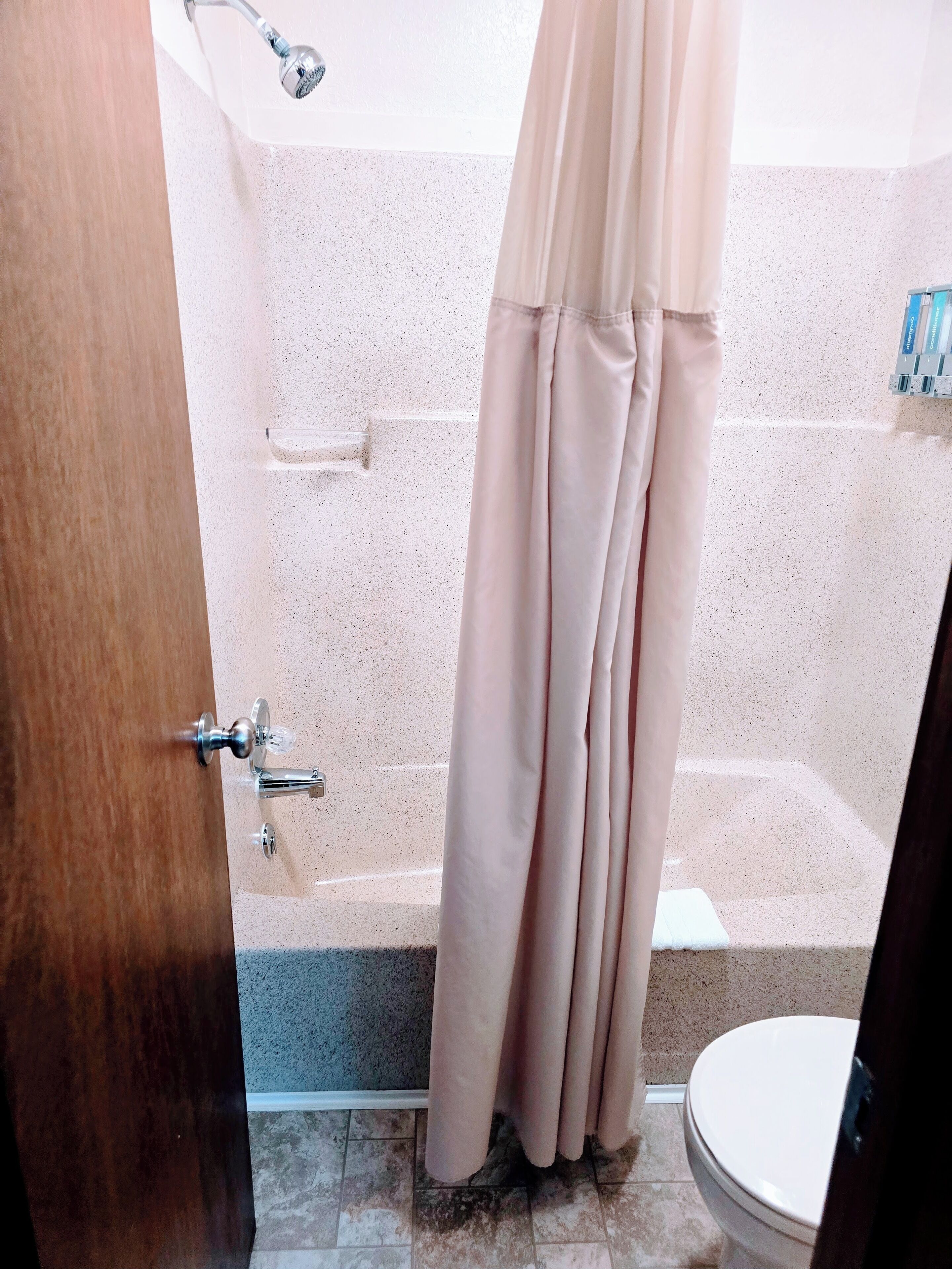 A bathroom with a shower, toilet, and a towel rack.