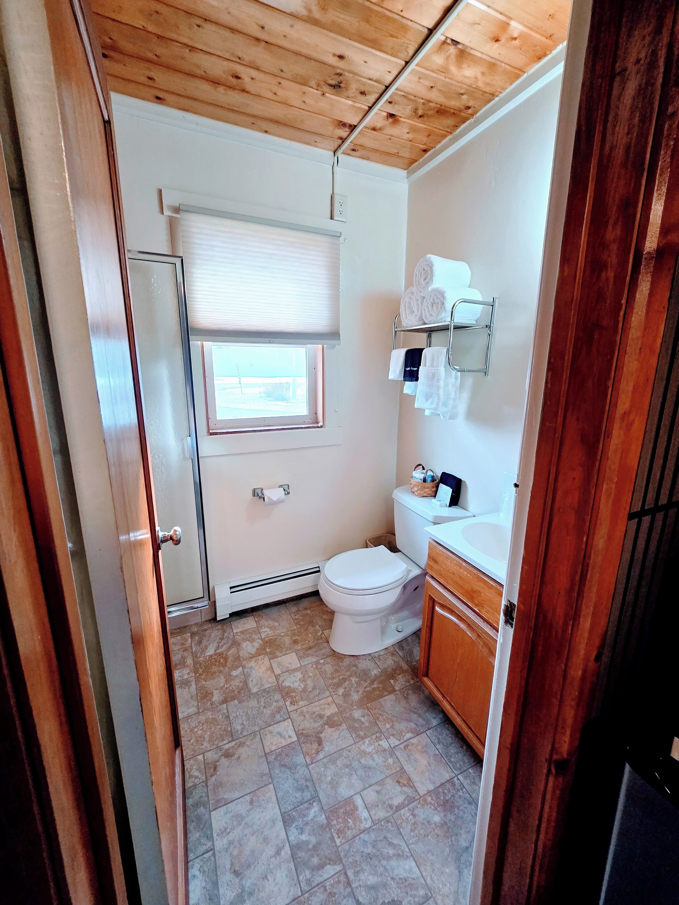 A compact bathroom with a toilet, a sink, and a window with blinds.