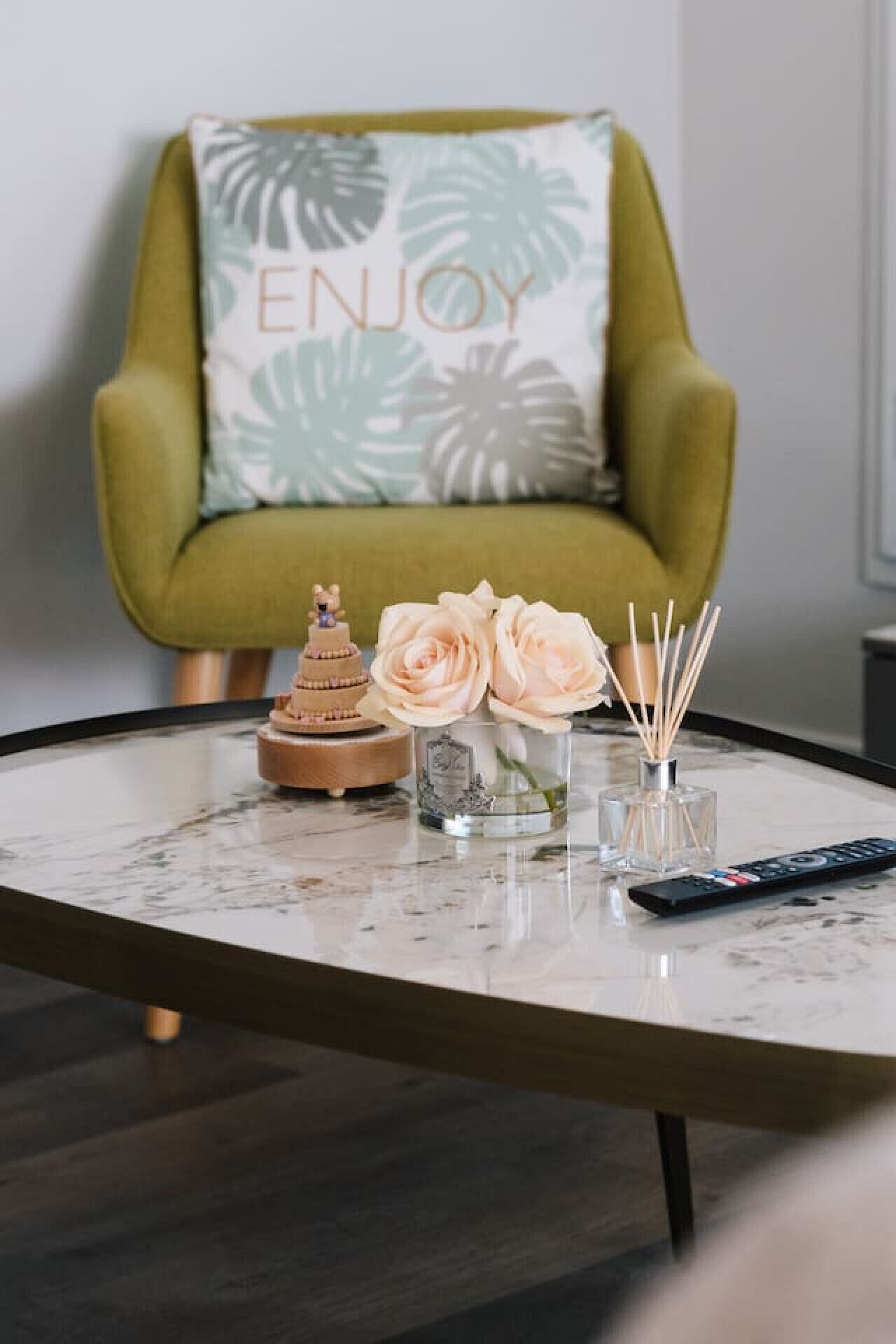 Ein runder Tisch mit einer kleinen Dekoration, einer Blumenvase und einer Fernbedienung.