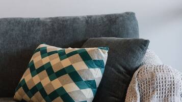 A grey sofa with a patterned pillow and a knitted throw.