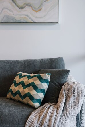 Ein graues Sofa mit einem gemusterten Kissen und einer gestrickten Decke.