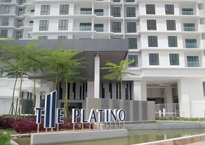 Un hôtel moderne avec une enseigne indiquant « THE PLATINO », situé devant un immeuble à plusieurs étages doté de balcons.