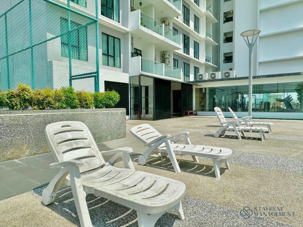 Un bâtiment moderne doté de nombreux balcons, d’un espace extérieur aménagé pour s’asseoir et d’une piscine.