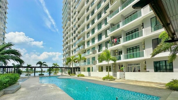 A swimming pool area with a modern building in the background. - The Platino Paradigm Mall by Stayrene (Johor Bahru)