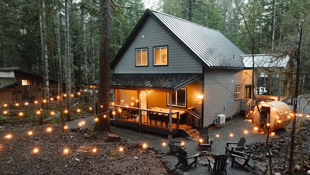 A cabin with a covered porch, a wooden deck, and a fire pit area. - Alpenwolf - Sauna! Hot Tub! Firepit! EV! AC! (Ashford)