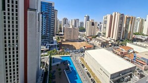 Un edificio alto con piscina, rodeado de otros edificios de gran altura.