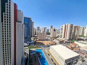 A high-rise building with a swimming pool, surrounded by other high-rise buildings. - Estúdios com piscina no lounge (São Paulo)