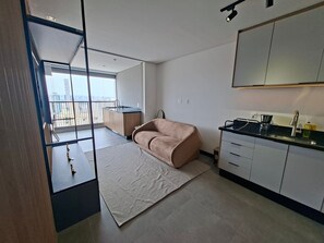 Eine moderne Wohnung mit Küchenzeile, einer Couch, einem großen Fenster und einem Balkon.
