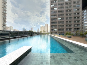 A swimming pool with a tiled deck, surrounded by high-rise buildings.