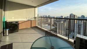 Un balcón con lavadora, una mesa y vistas a la ciudad.