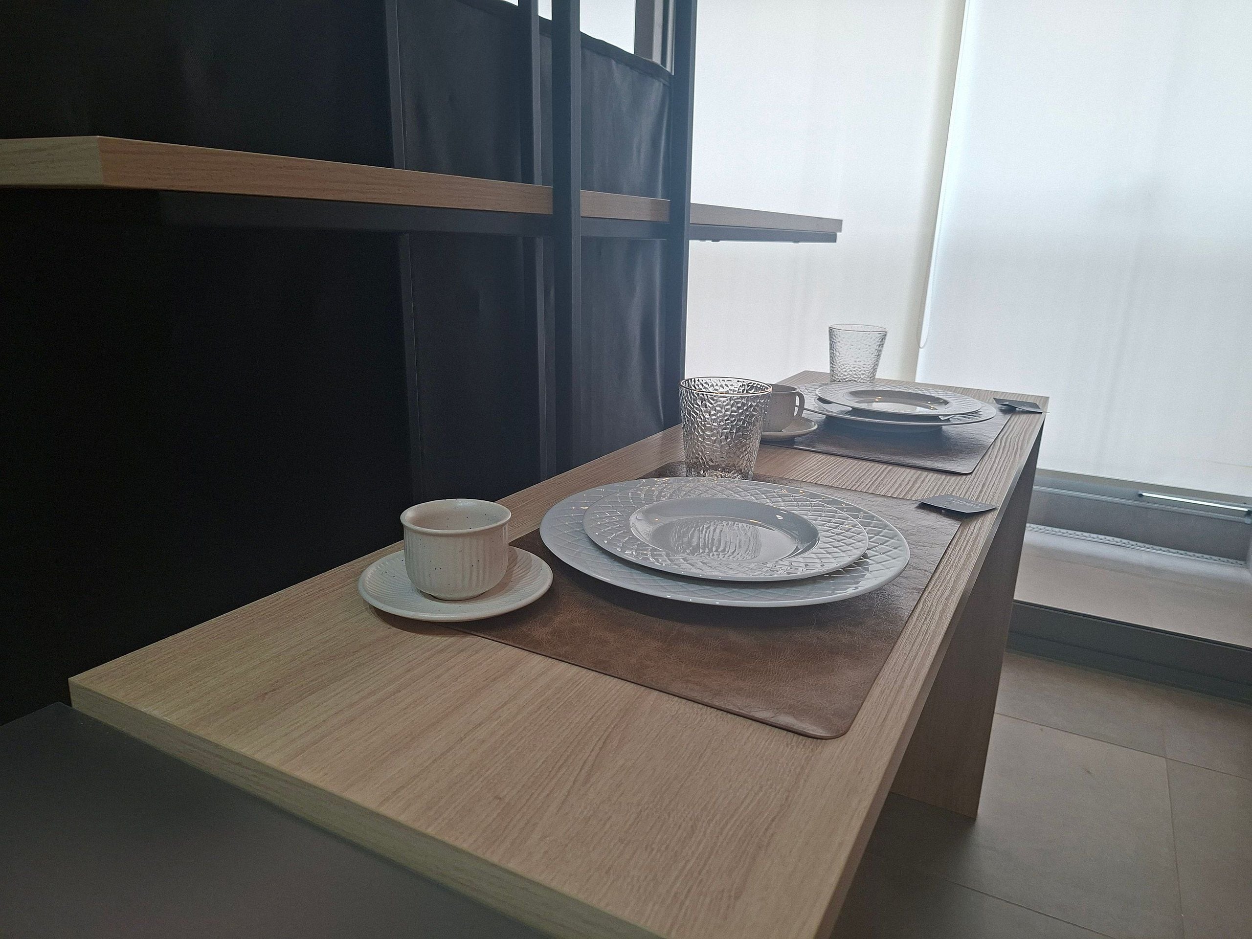 A neatly arranged dining table with plates, a cup, and cutlery.