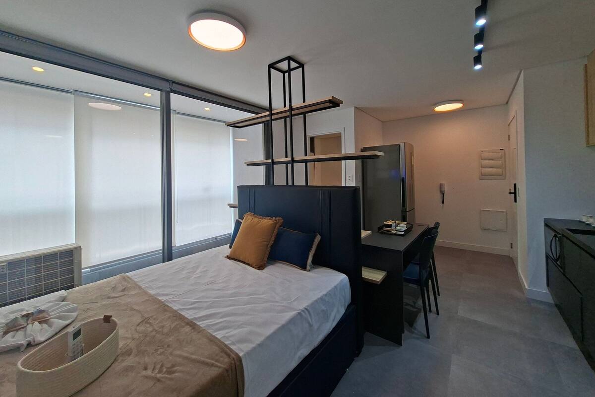 A modern hotel room with a bed, desk, and a large window.