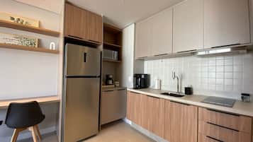 Eine moderne Küche mit einem Einbaukühlschrank, einer Mikrowelle, einer Kaffeemaschine und einem Spülbecken.