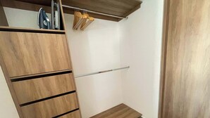 En garderob i trä med flera fack och en metallstång för att hänga upp kläder.