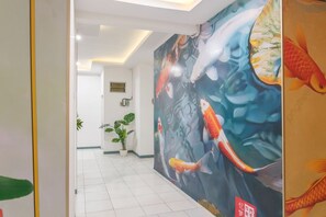 A hallway with a large mural of koi fish, a potted plant, and a door with a yellow stripe. - Dream Memory Semarang, by INNCA COLLECTION (Semarang)