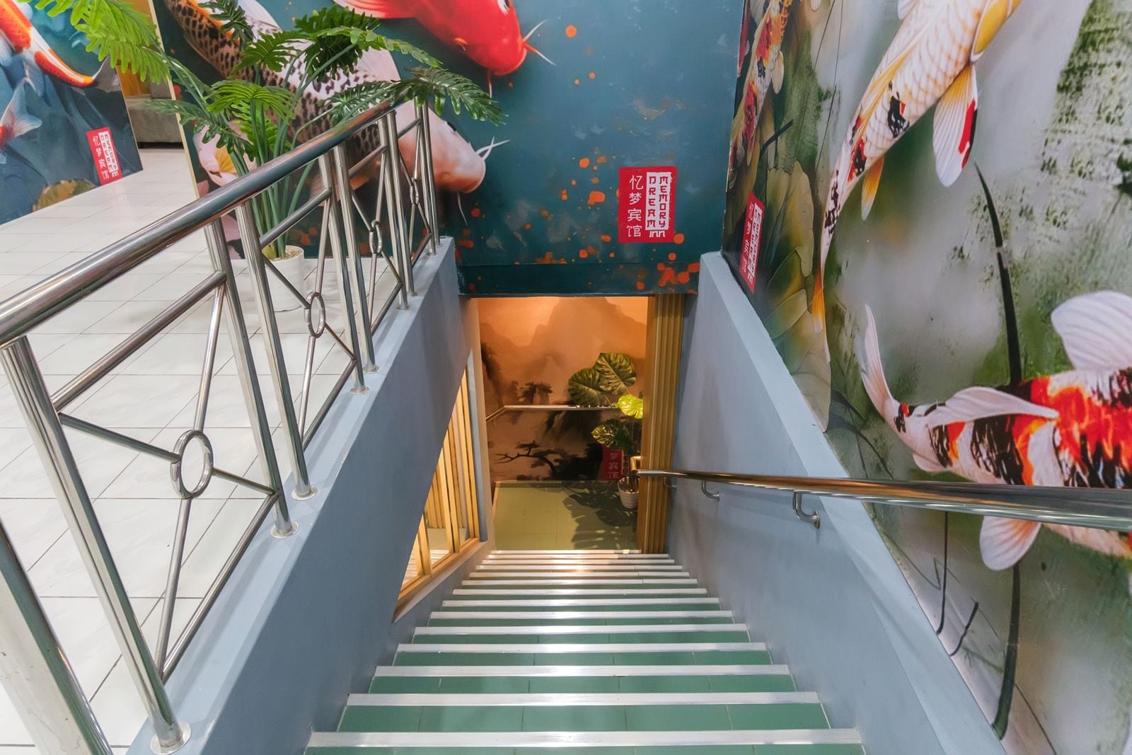 A staircase with metal railings and green steps leading to a room with a mural of fish and plants.