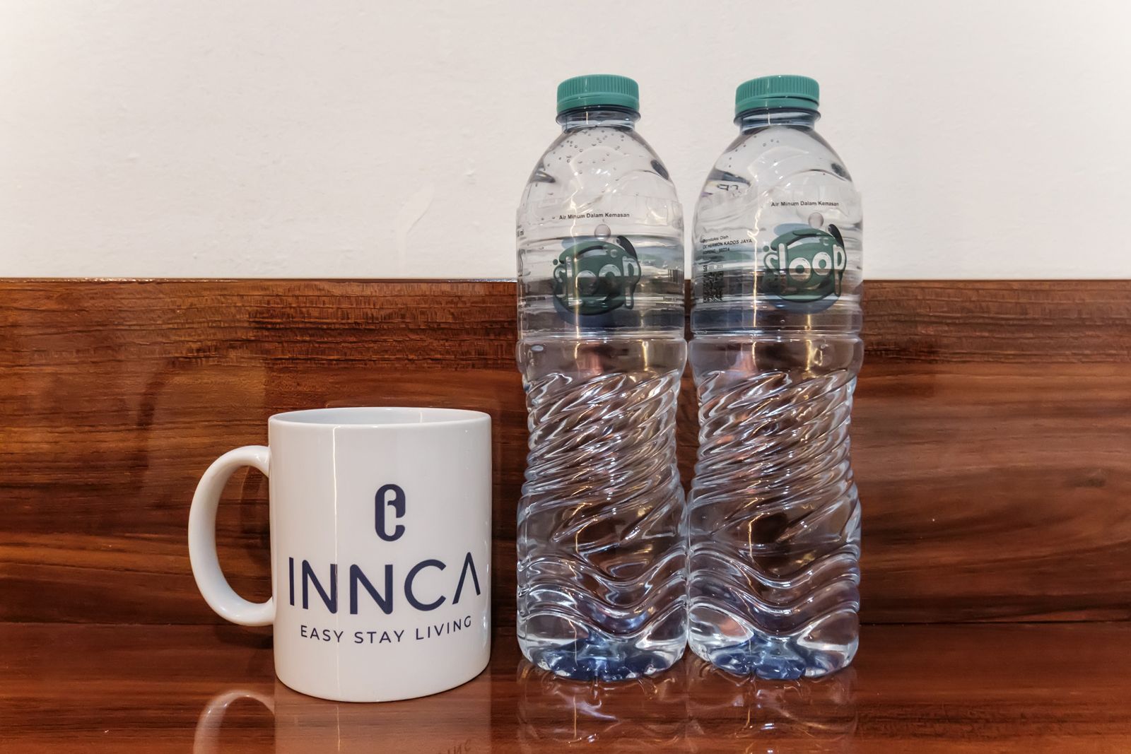 Una taza blanca con el logo 'C INNCA' y el eslogan 'EASY STAY LIVING' sobre una superficie de madera.
