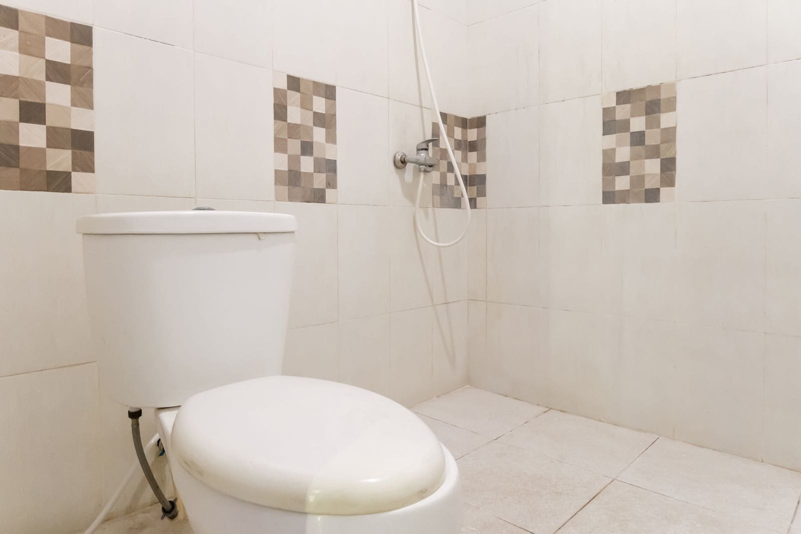 A bathroom with a toilet, a shower, and tiled walls.