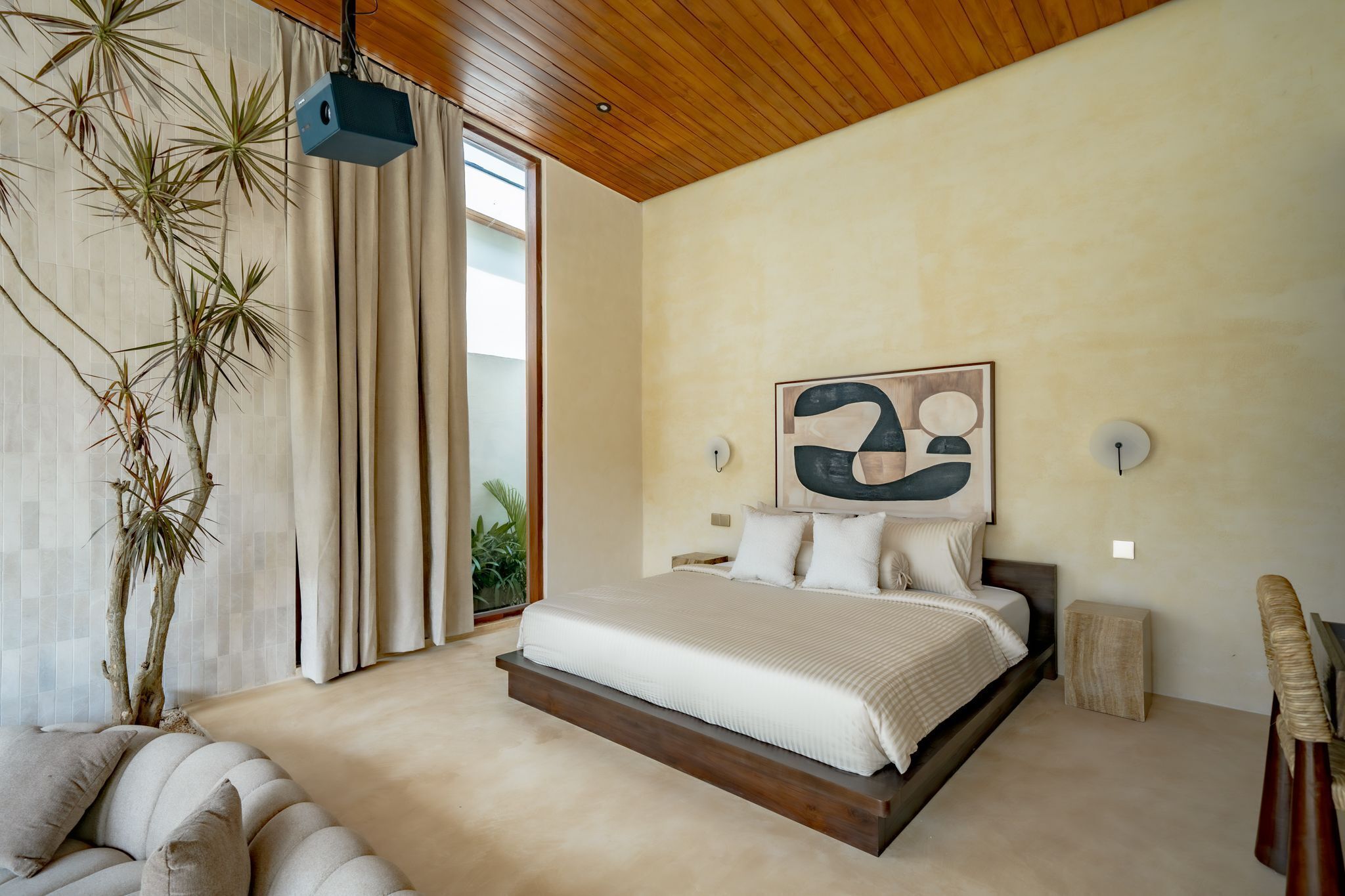 A modern bedroom with a large bed, a wooden ceiling, and a view of the outdoors.