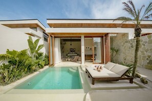 Un espace piscine extérieur moderne, doté de chaises longues et de plantes tropicales.