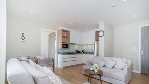 Ein modernes Wohnzimmer mit einer Couch, einem Couchtisch und einer Küche im Hintergrund.