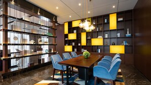 Un comedor moderno con una mesa de madera y sillas azules, rodeado de estanterías con paneles iluminados.
