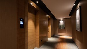 Un pasillo moderno con paneles de madera, una pantalla digital que muestra el año 2005 y obras enmarcadas en las paredes.
