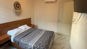 Ein Schlafzimmer mit einem Bett, einer Wand-Klimaanlage, einer Wanddekoration und einer Tür.