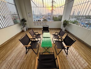 A conference room with a long table and chairs, large windows with metal bars, and potted plants. - Anh House (Da Nang)