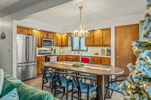 A modern kitchen with wooden cabinets, stainless steel appliances, and a central island with bar stools. - Tranquil Lake Harmony Spa Chalet, Hot Tub, Game Rm (Lake Harmony)