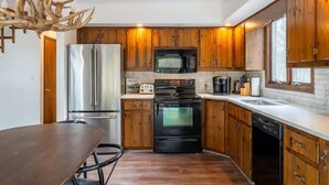 Eine moderne Küche mit Holzausstattung, Edelstahlgeräten und einer Kronleuchter.