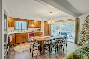 A modern kitchen with wooden cabinets, a dining table with chairs, and a large window. - Tranquil Lake Harmony Spa Chalet, Hot Tub, Game Rm (Lake Harmony)