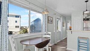 Eine Küche mit Essbereich, einem Kühlschrank und einem Fenster mit Blick auf ein Haus.