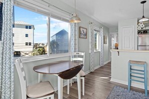 Eine Küche mit Essbereich, einem Kühlschrank und einem Fenster mit Blick auf ein Haus.