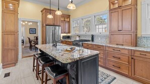 Eine geräumige Küche mit Holzausstattung, einer großen Kochinsel und Pendelleuchten.