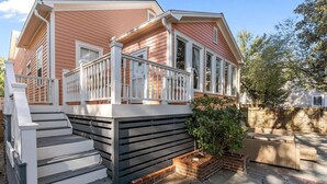 Ein zweistöckiges Haus mit Veranda, Treppe und Ziegelpflanzgefäß.