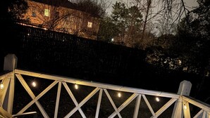 A wooden deck with a railing, string lights, and two chairs. - Peaceful Hideaway 1-bedroom apartment with king bed in charming Belhaven (Jackson)