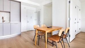 A modern kitchen with white cabinets, a wooden dining table with four chairs, and a visible water tap. - Blueground | Gowanus, view, nr Prospect Park (New York)