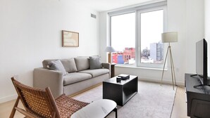 A modern living room with a sofa, a coffee table, a floor lamp, and a TV. - Blueground | Gowanus, view, nr Prospect Park (New York)