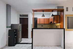 A compact kitchen with a central island, a refrigerator, and a microwave. - INNCA Singa Utara, Semarang (Semarang)