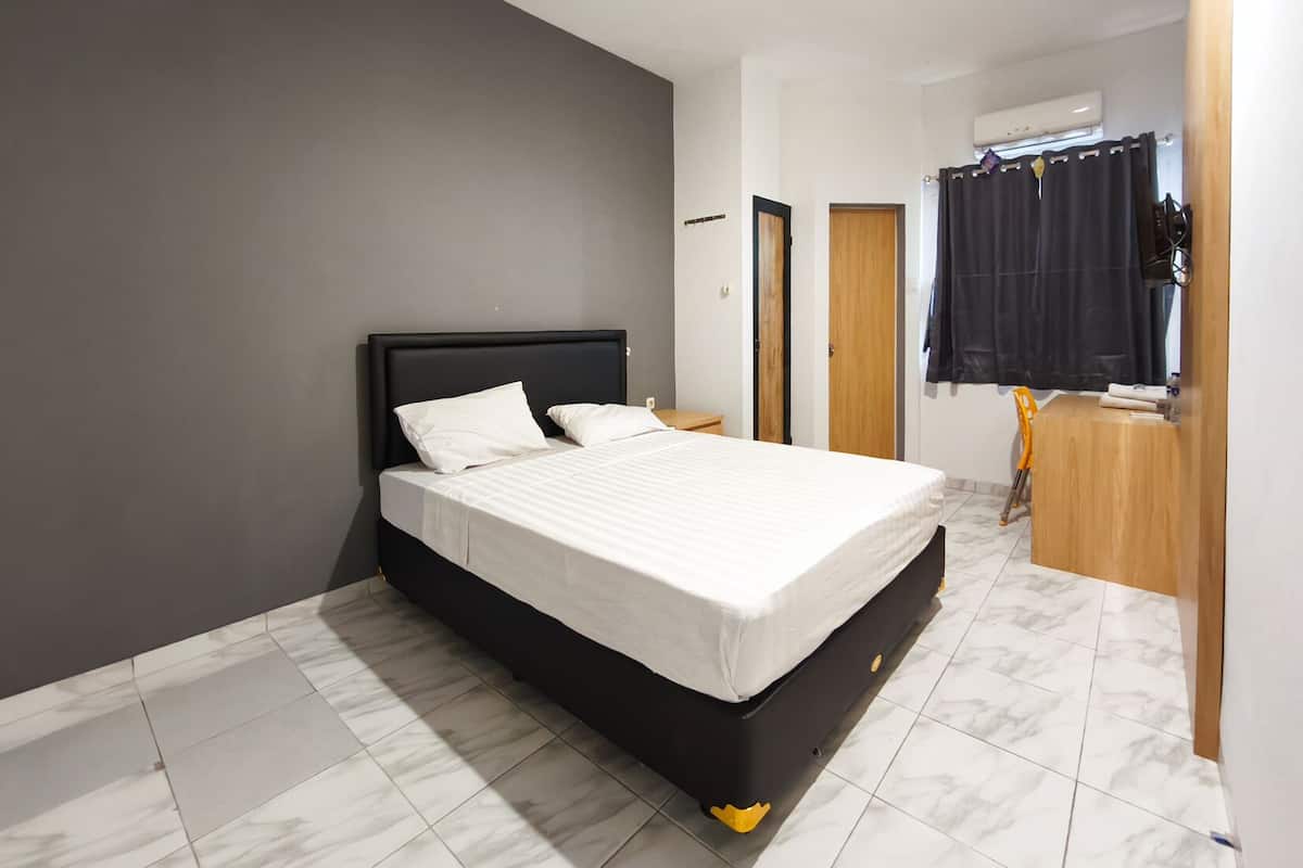 Un dormitorio moderno con cabecera negra, ropa de cama blanca y suelo de baldosas de mármol.