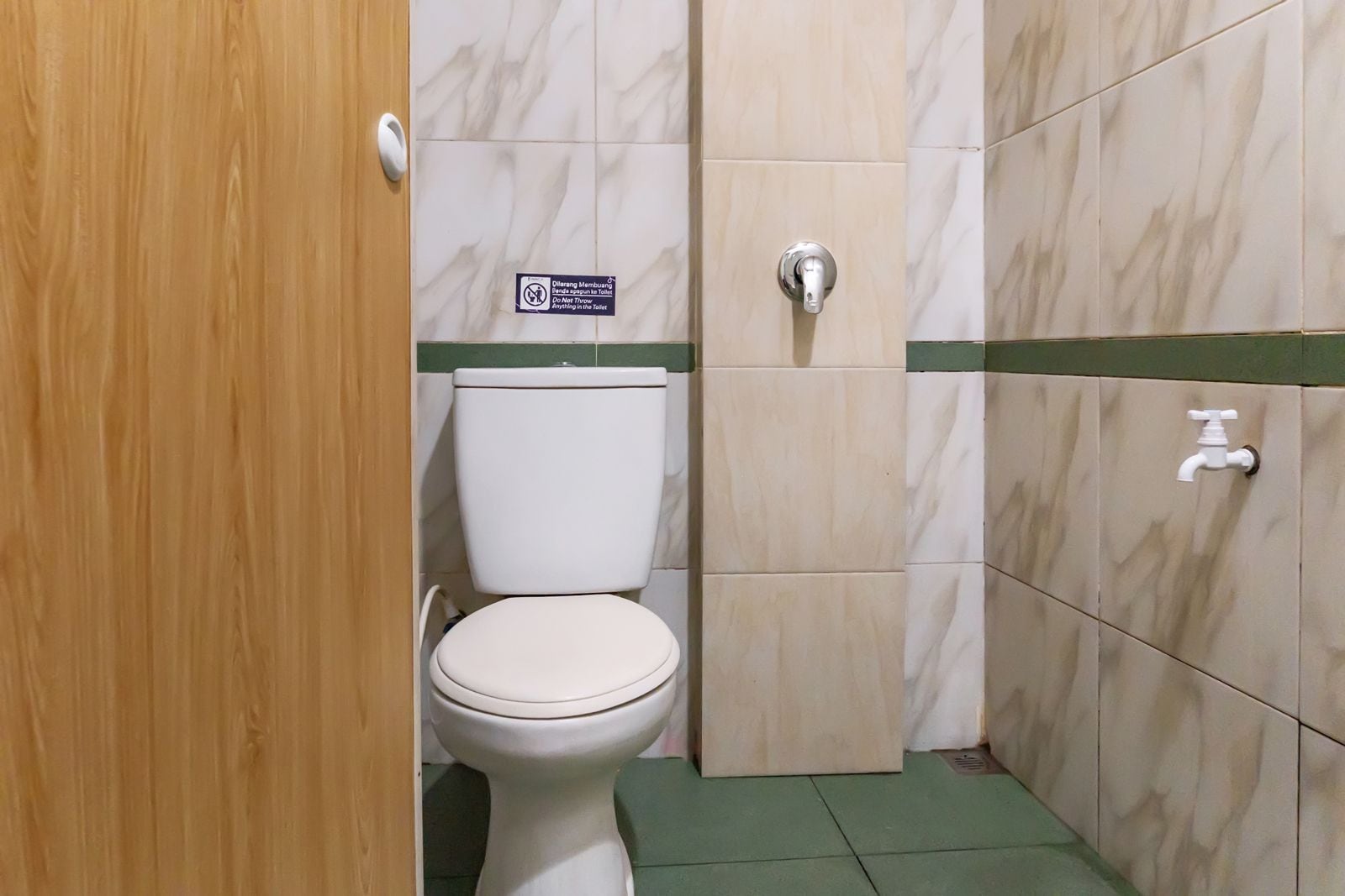 A bathroom with a toilet, a hand dryer, and a sign indicating no flushing of non-litter items.