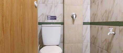 A bathroom with a toilet, a hand dryer, and a sign indicating no flushing of non-litter items.