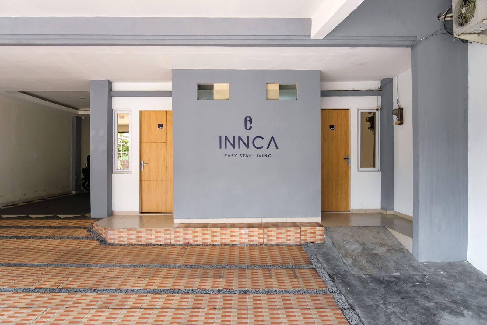 A hotel entrance with a grey sign reading 'INNCA EASY STAY LIVING'.