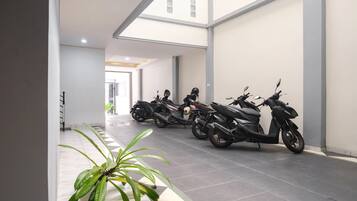 A modern indoor space with a row of parked scooters, a staircase, and a potted plant.