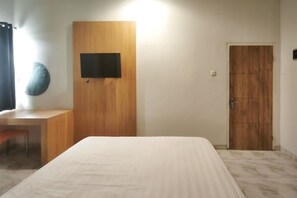 Ein Schlafzimmer mit einem Bett, einem Holztisch, einem an der Wand montierten Fernseher und einer Tür.