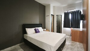 A hotel room with a bed, a nightstand, a bathroom with a shower, and a window with curtains. - INNCA Singa Utara, Semarang (Semarang)