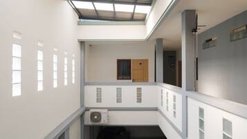 Ein mehrgeschossiges Interieur mit einer zentralen Treppe, einem Deckenventilator und einer Tür mit Fenster.