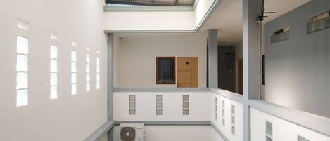 Un interno a più livelli con una scala centrale, una ventola a soffitto e una porta con finestra.